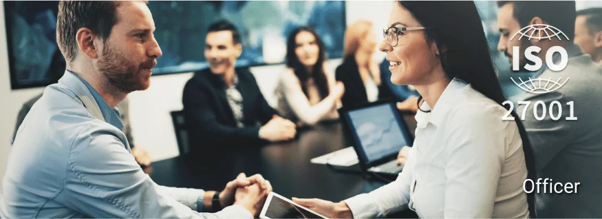 Personengruppe im Besprechungsraum, im Vordergrund zwei Personen mit Tablet im Gespräch, eingeblendet ISO 27001-Siegel – Darstellung für ISO 27001 Officer Training im Bereich Informationssicherheit.