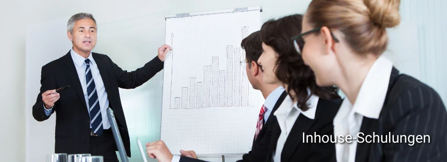 Dozent präsentiert an Flipchart vor Business-Gruppe – symbolisiert Inhouse-Schulungen im professionellen Unternehmensumfeld.