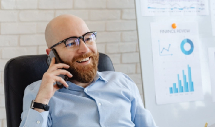 IT-Sicherheitsbeauftragter telefoniert am Arbeitsplatz vor Sicherheits- und Analysecharts als Symbol für Schulungen zu ISB- und IT-Rollen in Organisationen.