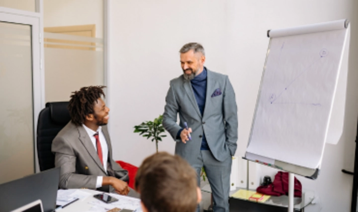 Trainer präsentiert Strategieinhalte am Flipchart vor Geschäftsführung im Schulungsraum als Symbol für praxisorientierte Managementschulung.